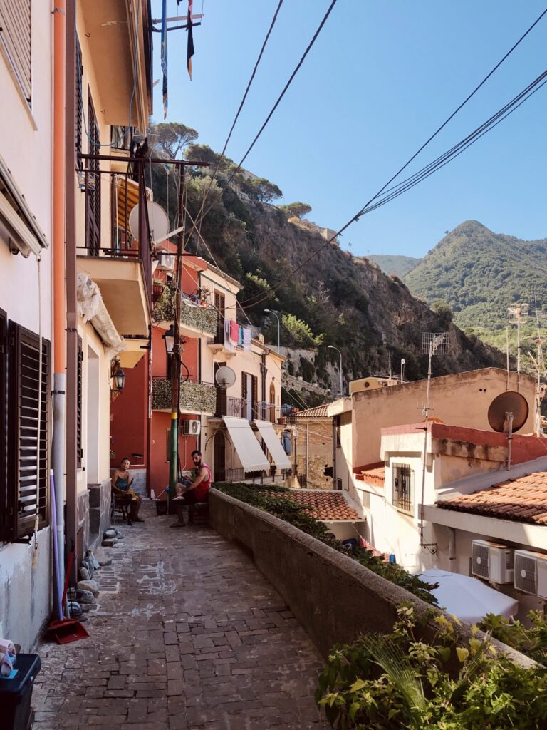 Case pastello di San Giorgio, centro storico di Scilla, con due abitanti incuriositi dall'obiettivo fotografico