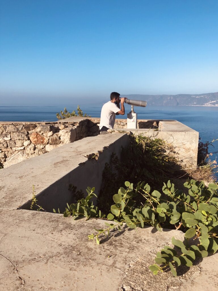 Ragazzo che osserva dall'alto del Castello Ruffo la vista sul mare con il telescopio panoramico